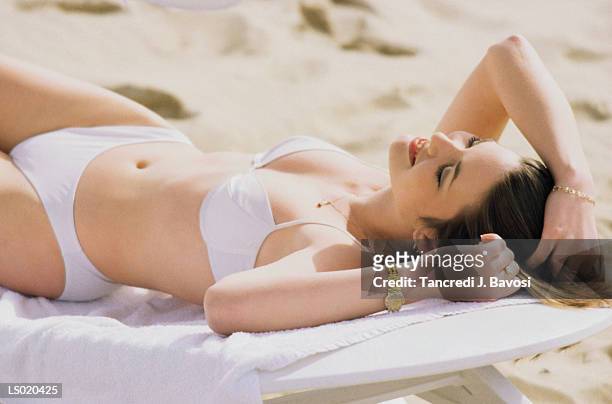young woman sunbathing on a beach - bavosi ストックフォトと画像