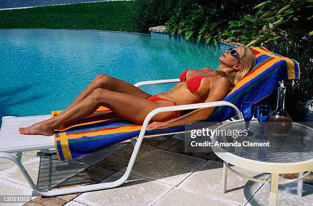 woman sunbathing by swimming pool - amanda and amanda fotografías e imágenes de stock
