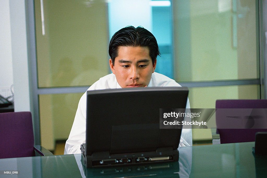 Man working on laptop computer in boardroom