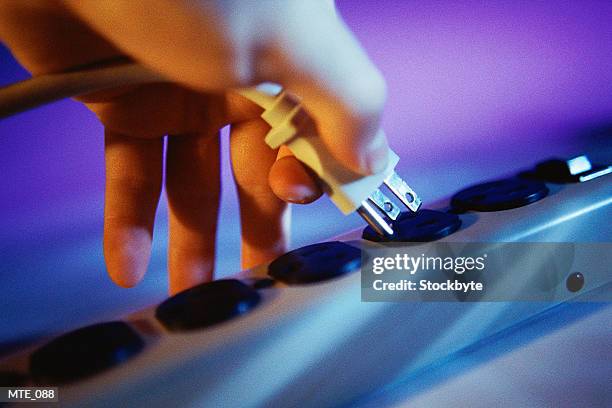 hand plugging cord into power bar - steckerleiste stock-fotos und bilder