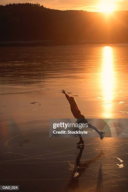 woman figure skating on lake at sunset - figure skating woman stock pictures, royalty-free photos & images