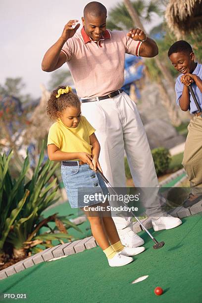 father, son and daughter playing miniature golf - mini golf stock-fotos und bilder