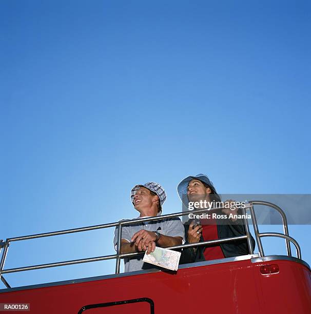 man and woman riding on top deck of double-decker bus, low angle view - a ross stock-fotos und bilder