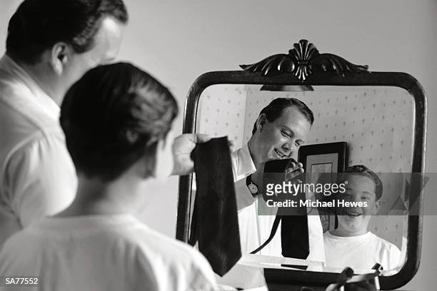 father and son (12-14) choosing tie, reflection in mirror (b&w) - reflection foto e immagini stock
