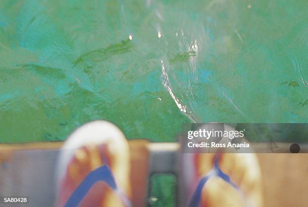 person wearing flip-flops on platform over sea, close-up - a ross stock-fotos und bilder