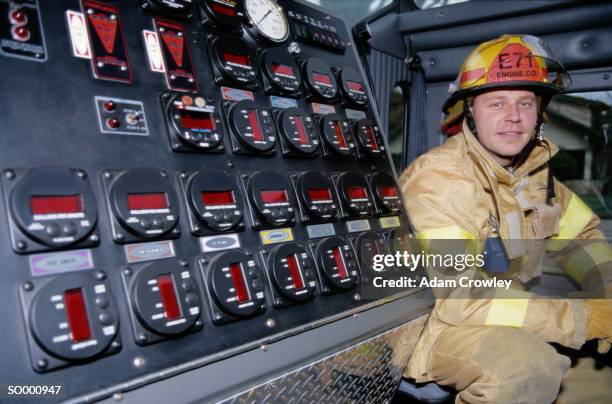 firefighter sitting next to a control panel - next stockfoto's en -beelden