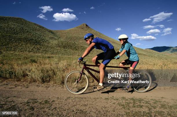 couple riding a tandem bicycle - tandem ストックフォトと画像