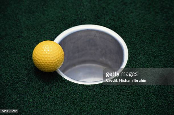 yellow golf ball and hole - off target stock-fotos und bilder