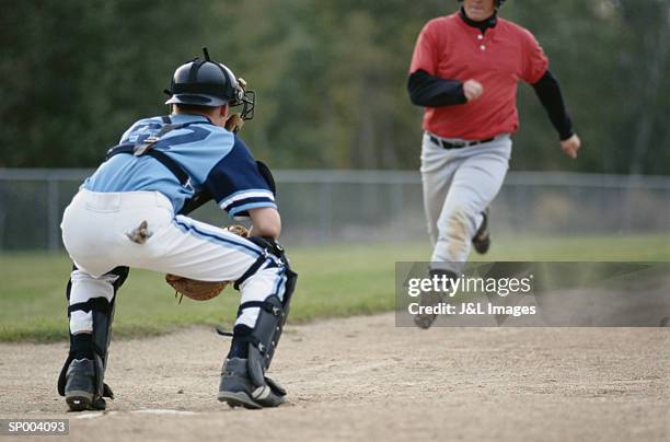 baseball player running to home base - base sports equipment stock-fotos und bilder