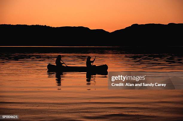 two people paddling canoe on lake, silhouette, sunset - sunset lake imagens e fotografias de stock