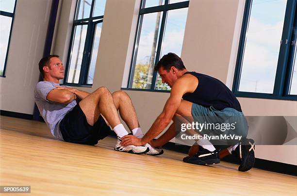 man assisting another man doing sit-ups - duing stock pictures, royalty-free photos & images