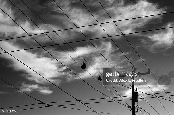 shoes hanging from utility lines, silhouette, low angle view (b&w) - alex grey stock-fotos und bilder