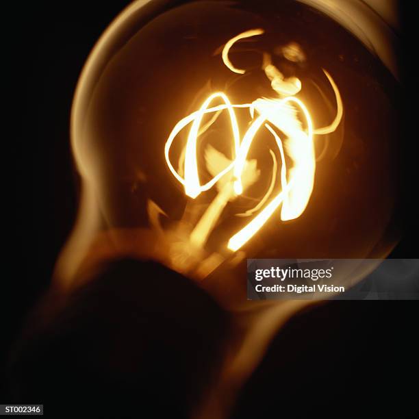 glowing light bulb filament, close-up - filament stock-fotos und bilder