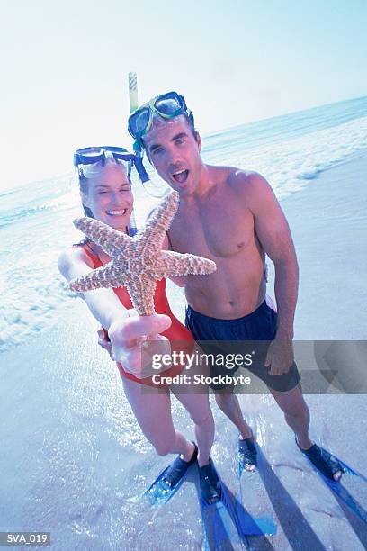 woman and man wearing snorkeling gear; woman holding starfish - wearing stock-fotos und bilder