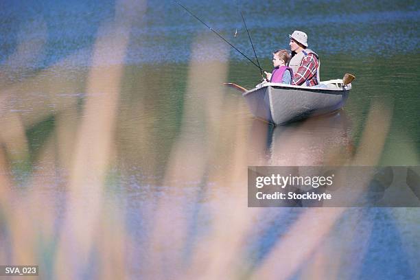 man and boy sitting in rowboat and fishing - gestalt stock-fotos und bilder