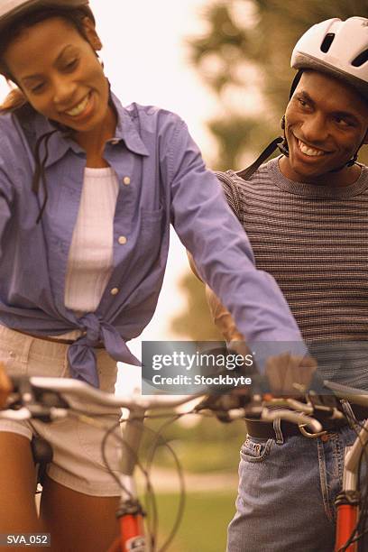 woman and man riding bicycles; both wearing helmets and smiling - wearing stock-fotos und bilder