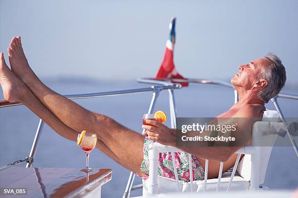 mature man reclining in deck chair on boat - only mature men fotografías e imágenes de stock