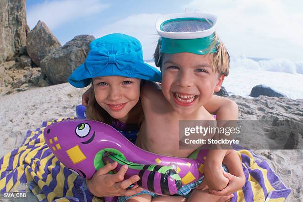 boy and girl sitting together on beach towel - recreational equipment stock pictures, royalty-free photos & images