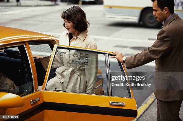 woman and man entering a taxi - yellow taxi fotografías e imágenes de stock