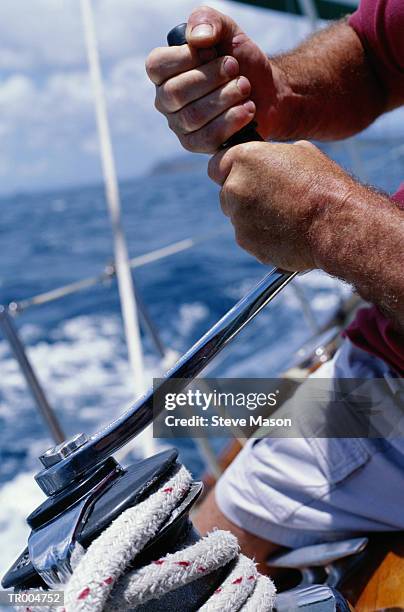 man cranking capstan on sailboat, close-up - cabestano foto e immagini stock