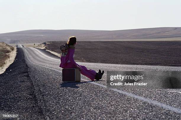 hitchhiker sitting on suitcase - gestalt stock-fotos und bilder