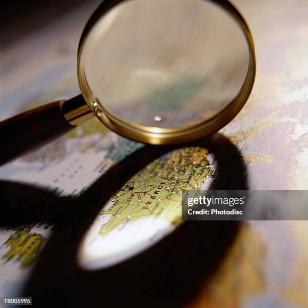 shadow of magnifying glass on map of france - france foto e immagini stock