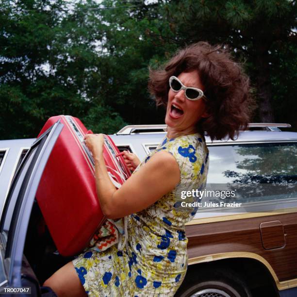 frustrated woman putting luggage in the car - sólo mujeres de mediana edad fotografías e imágenes de stock