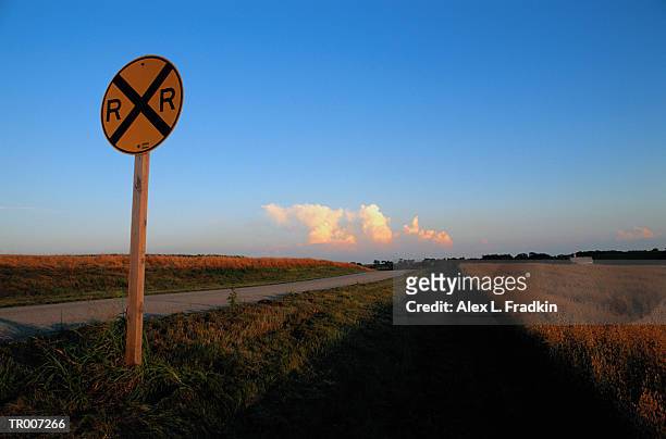 railroad crossing sign by empty road through farmland - by stock pictures, royalty-free photos & images
