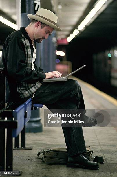 man using a laptop while waiting for the subway - tommy hilfiger and gq honor the men of new york at the tommy hilfiger fifth avenue flagship stockfoto's en -beelden