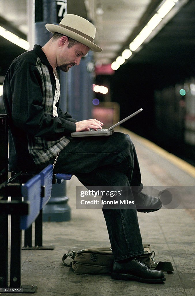 Man Using a Laptop While Waiting for the Subway