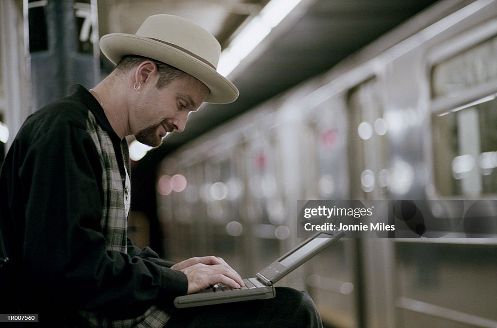 Man Using a Laptop While Waiting for the Subway
