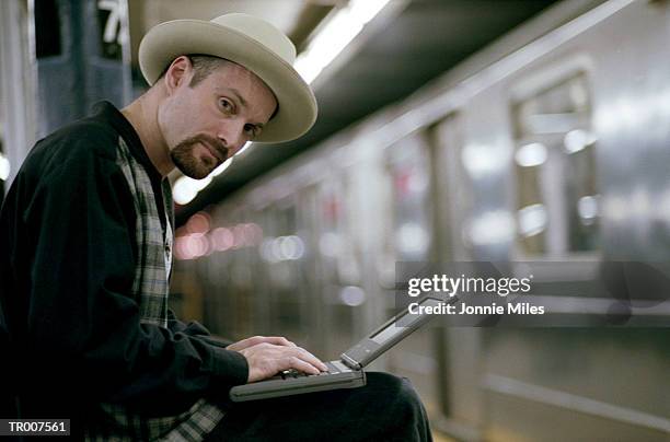 portrait of man using laptop in a subway terminal - a stock pictures, royalty-free photos & images