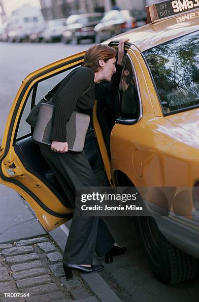 businesswoman getting into a taxi - only mid adult women imagens e fotografias de stock