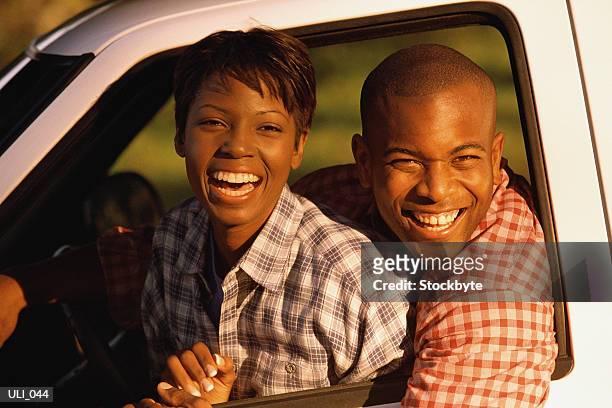 woman and man leaning out of driver's side window of vehicle, smiling - get out stock pictures, royalty-free photos & images