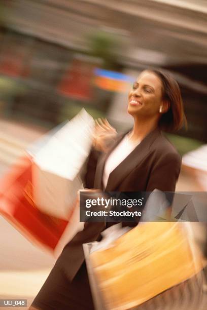 woman walking on street, carrying shopping bags, smiling - only mid adult women stock-fotos und bilder