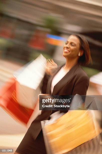woman walking on street, carrying shopping bags, smiling - only mid adult women stock pictures, royalty-free photos & images