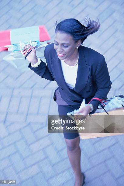 woman running along brick sidewalk, carrying shopping bags - only mid adult women stock-fotos und bilder