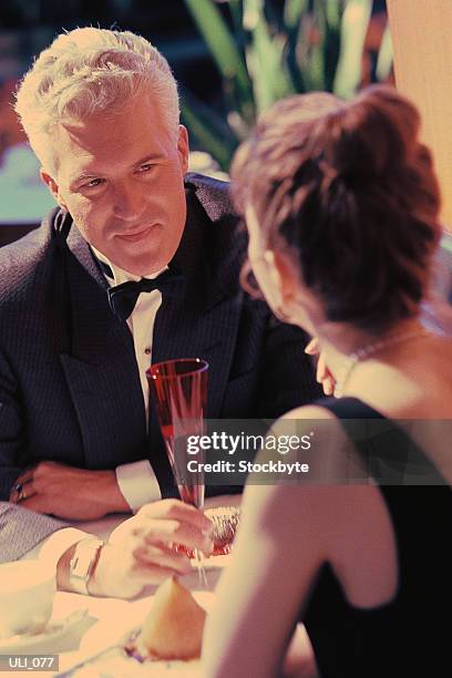 man and woman sitting at restaurant table, looking at one another - aother stock pictures, royalty-free photos & images