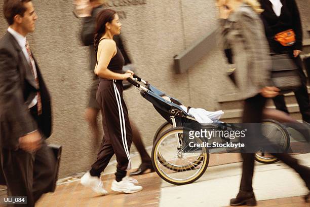 woman in exercise clothes, pushing three-wheeled baby carriage - three wheeled pushchair fotografías e imágenes de stock