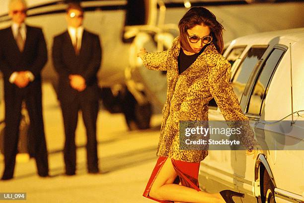 woman standing beside car, lifting heel, looking at leg - general aviation stock pictures, royalty-free photos & images