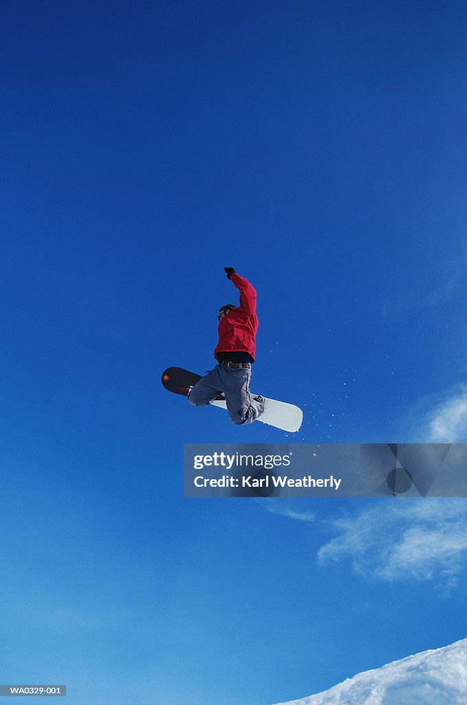 Male snowboarder in mid-air, low angle view