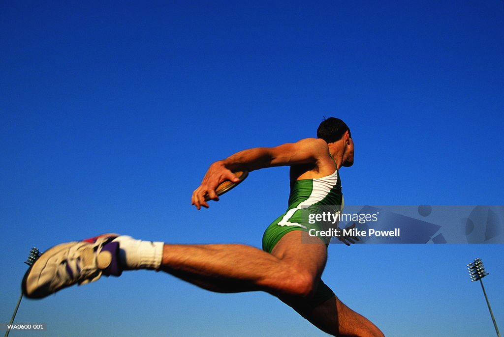 Male athlete holding discus, low angle view