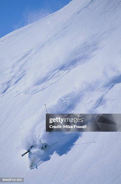 skier falling down slope, engulfed in cloud of snow - wipeout sportunfall stock-fotos und bilder