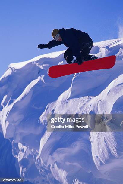 male snowboarder jumping off ridge, close-up, low angle view - snowboard jump close up stock pictures, royalty-free photos & images