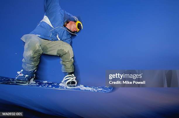 male snowboarder in mid-jump, low angle view (blurred motion) - snowboard jump close up stock pictures, royalty-free photos & images
