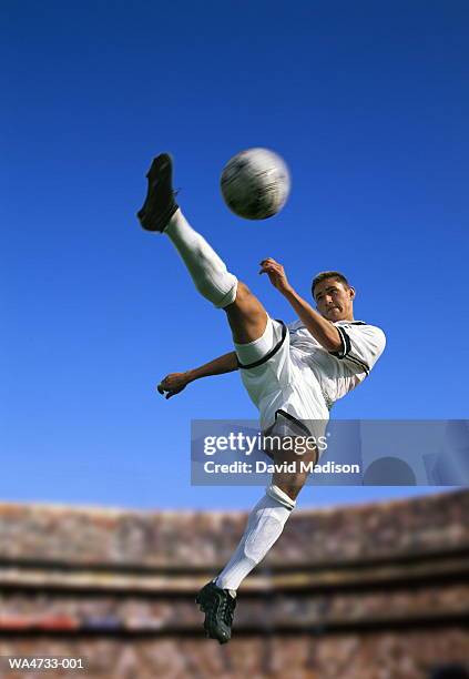 soccer player in mid air, kicking ball - volear fotografías e imágenes de stock