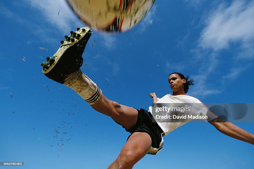 Soccer player kicking ball, low angle view, close-up