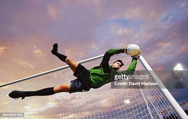 soccer goalie catching ball in mid-air - goalkeeper soccer stock-fotos und bilder