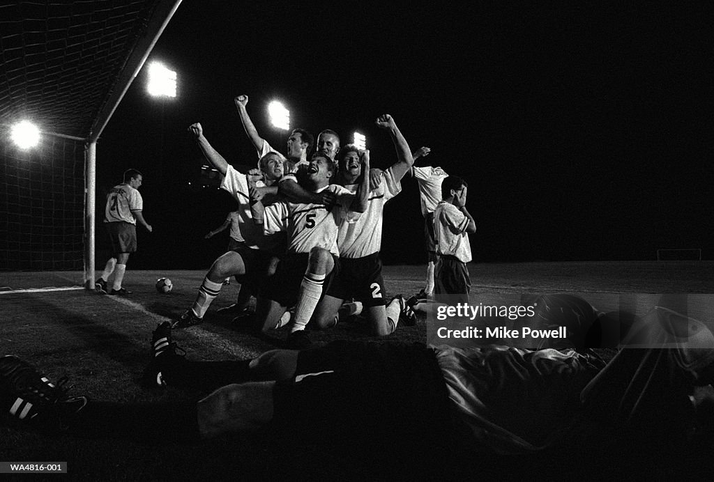 Soccer team celebrating goal by net