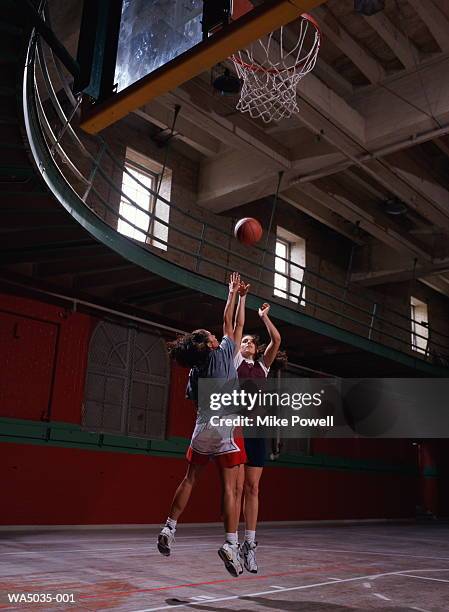 two women playing basketball on indoor court - womens college basketball stock-fotos und bilder